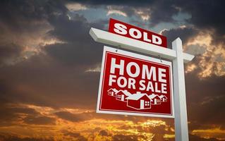 rojo vendido casa en venta signo de bienes raíces sobre el cielo del atardecer foto