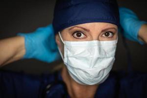 Female Doctor or Nurse Wearing Surgical Gloves Putting On Medical Face Mask photo