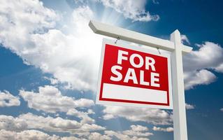 For Sale Real Estate Sign over Clouds and Blue Sky photo