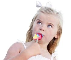 adorable niña disfrutando de su piruleta en blanco foto