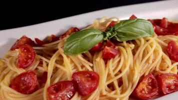 espaguetis con tomate en un plato, listos para servir. sirviendo pasta con tomates. salsa de tomate y albahaca. tiro deslizante. Comida típica de restaurante de comida italiana. hecho en casa. comida italiana video