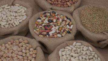 Legumes dry mixed various beans, lentils, chickpeas rotating on jute bowl video