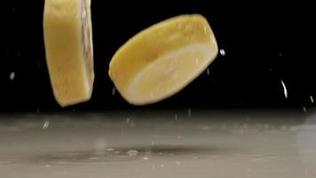 Fresh sliced lemon falling and splashing on water at slow motion video