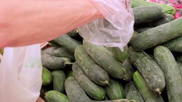 Picking cucumber at the vegetables market. Hand choosing healthy vegetarian food in grocery store at slow motion. video
