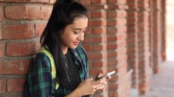 Video clip of a female college student typing text on her mobile phone on the college campus.