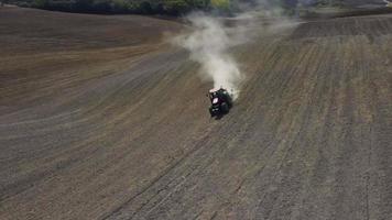 Tractor preparing wheat rural field, plowing ground soil aerial view video