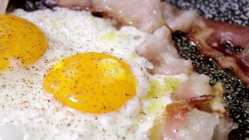 cozinhar ovos e bacon em óleo. fritar ovos no café da manhã inglês. pimenta deliciosa derramada. cozinhar em uma panela video