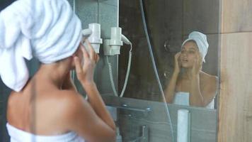 Woman applies moisturizer in front of mirror video