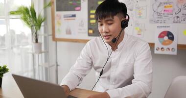 Side view of Happy male wears headset video calling on laptop. Businessman webinar speaker streaming live web training. Call center agent, service support manager speaking to distance customer.