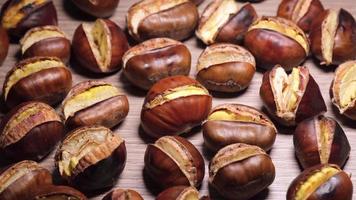 Roasted chestnuts illuminated on wooden background. video