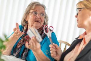 Financial Consultant Handing Scissors to Senior Lady Holding Credit Cards photo