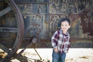 Cute Young Mixed Race Boy Having Fun Near Antique Machinery photo