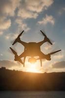 Silhouette of Unmanned Aircraft System UAV Quadcopter Drone In The Air At Sunrise. photo