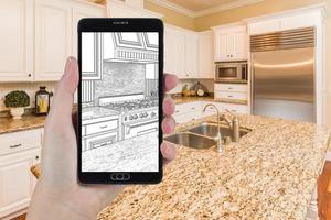 Hand Holding Smart Phone Displaying Drawing of Kitchen Photo Behind