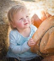 adorable niña con sombrero de vaquero en el huerto de calabazas foto