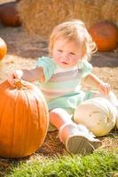 adorable niña divirtiéndose en un rancho rústico en el huerto de calabazas. foto