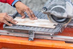 Worker Using Wet Tile Saw to Cut Wall Tile At Construction Site photo