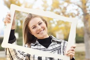 Pretty Young Woman Smiling in the Park with Picture Frame photo