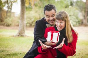 Mixed Race Couple Sharing Christmas or Valentines Day Gift Outside photo