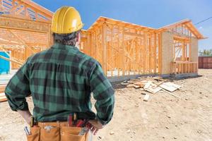 Contractor Standing Outside Construction Framing of New House. photo