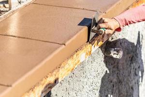 Construction Worker Using Stainless Steel Edger On Wet Cement Forming Coping Around New Pool photo