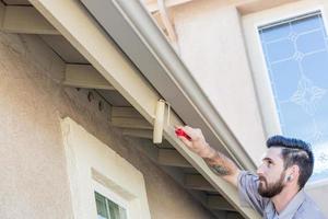 pintor profesional que usa un rodillo pequeño para pintar la fascia de la casa foto