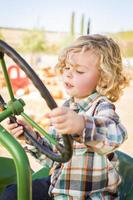 niño divirtiéndose en un tractor en un rancho rústico en el huerto de calabazas. foto