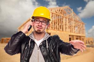 Young Cunstruction Worker on Cell Phone In Front of House photo