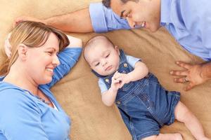 Young Mixed Race Couple Laying With Their Infant On A Blanket photo