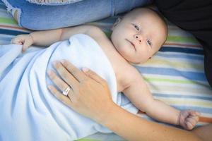 niño pequeño envuelto en su manta descansando con mamá foto