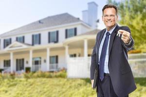 agente inmobiliario con llaves de casa frente a casa foto