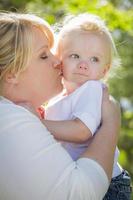 joven madre besando y sosteniendo a su adorable bebé foto
