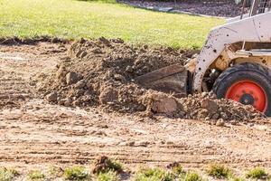 Small Bulldozer Digging In Yard For Pool Installation photo