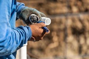 Plumber Applying Pipe Cleaner, Primer and Glue to PVC Pipe At Construction Site photo
