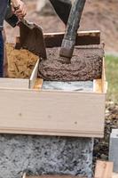 Construction Workers Pouring And Leveling Wet Cement Into Wood Framing photo