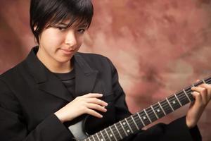 Multiethnic Girl Poses with Electric Guitar photo