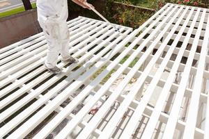 Professional Painter Rolling White Paint Onto The Top of A Home Patio Cover. photo