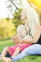 Mother and Little Girl Having Fun Together in Grass photo