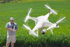 piloto que vuela aviones no tripulados drone recopilando datos sobre el campo de tierras de cultivo del país foto