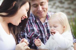 adorable niña comiendo una galleta con mamá y papá foto