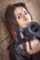 joven fotógrafa iraní adulta contra la pared sosteniendo la cámara. foto