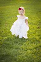 Adorable Little Girl Wearing White Dress In A Grass Field photo