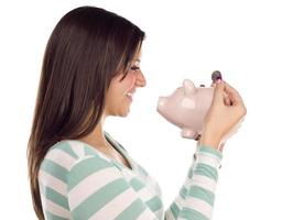 Ethnic Female Putting Coin Into Piggy Bank on White photo