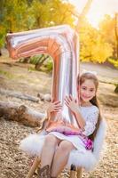 Linda niña jugando con globo mylar número siete al aire libre foto