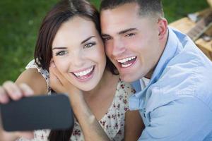 Mixed Race Couple Taking Self Portrait in Park photo