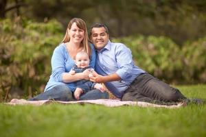 Happy Mixed Race Family Having a Picnic and Playing In The Park photo