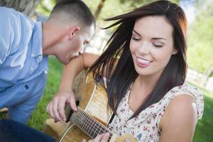 Mixed Race Couple at the Park Playing Guitar and Singing photo