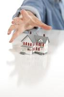 Womans Hand Reaching for Model House on White photo