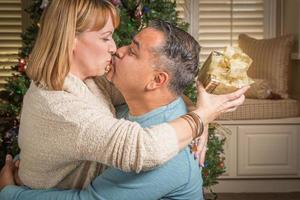 Young Mixed Race Couple with Present Near Christmas Tree photo