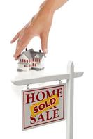 mano de mujer eligiendo casa con signo de bienes raíces vendidos foto